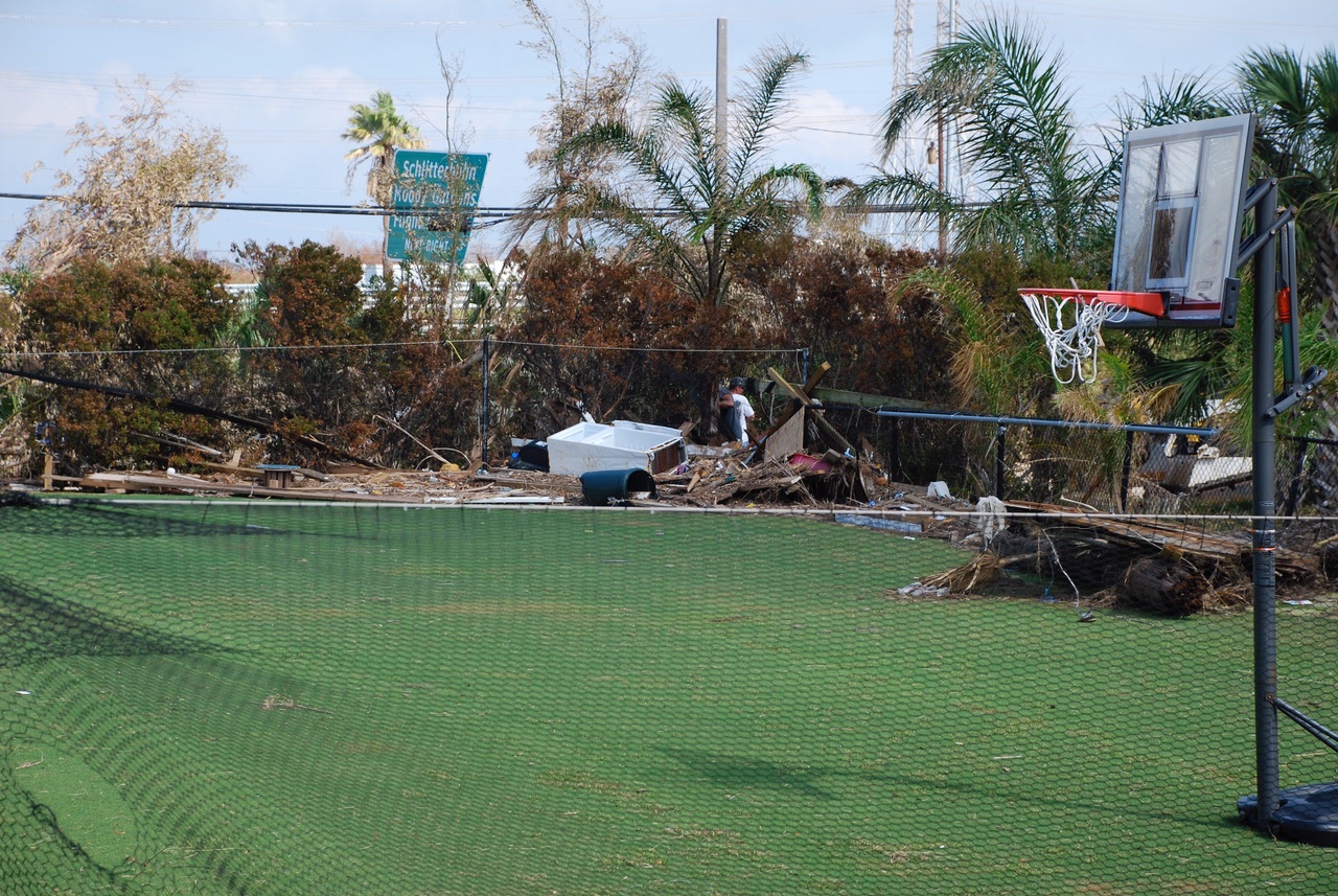 Debris piled along the fence line of the court after Hurricane Ike