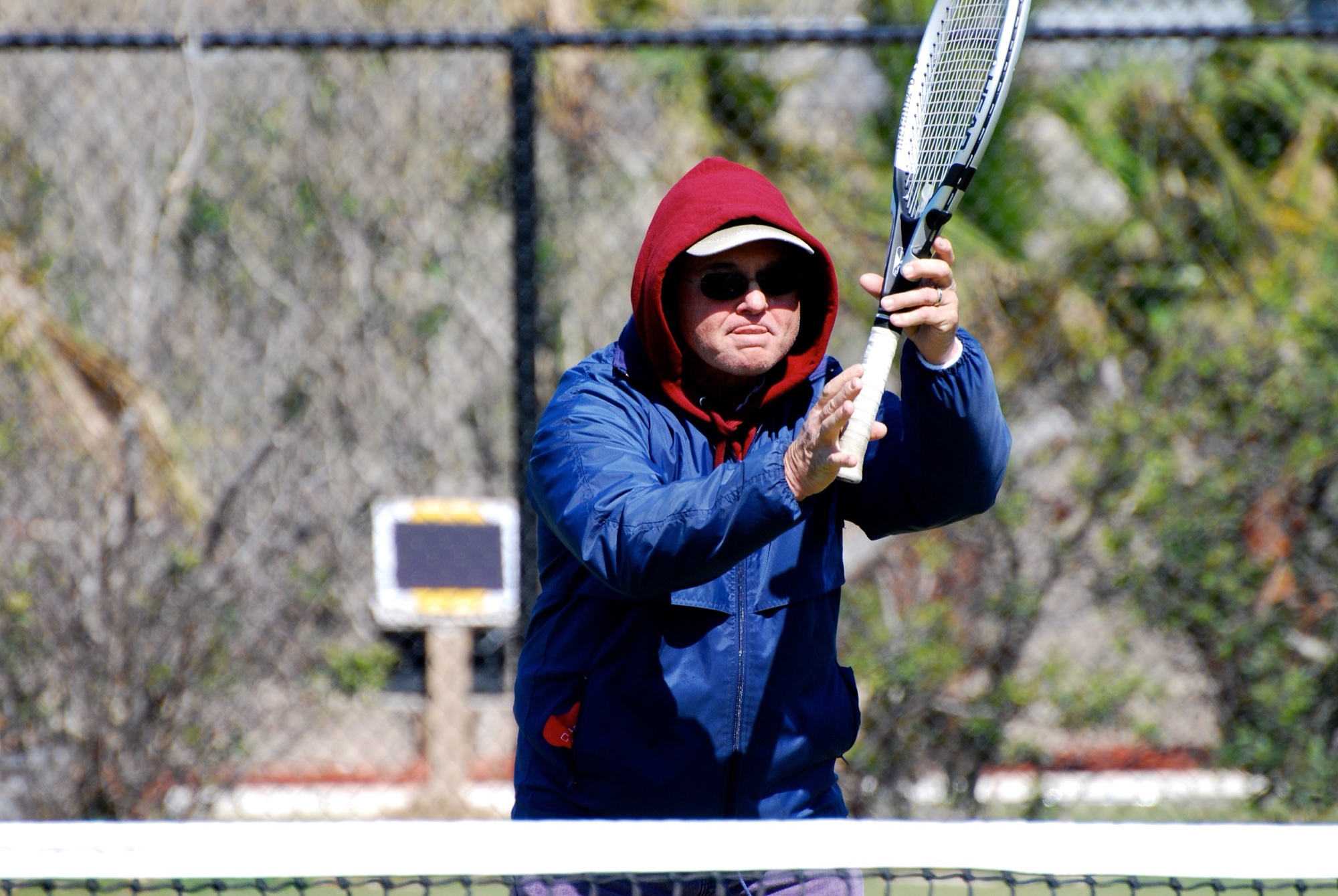 Waiting at the net in a hood and sunglasses